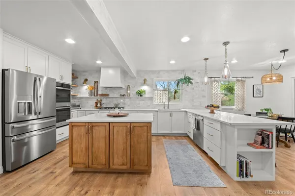 a kitchen with stainless steel appliances granite countertop a sink a stove a refrigerator and island with wooden floor
