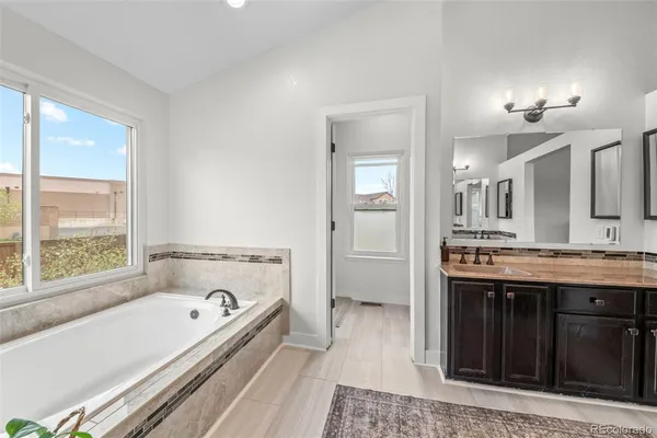 a bathroom with a granite countertop tub a double vanity sink and a large mirror