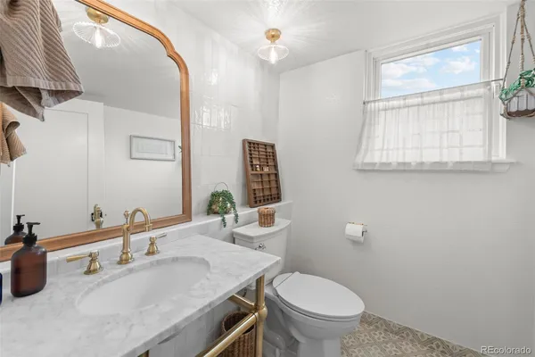 a bathroom with a granite countertop toilet a sink and a mirror
