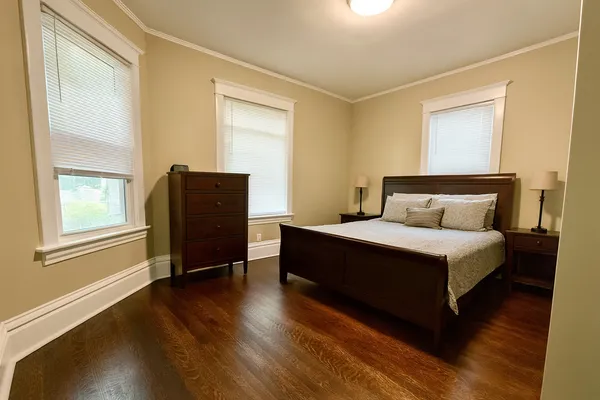 a bedroom with a bed window and wooden floor