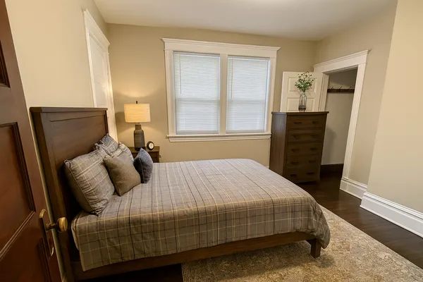 a bedroom with a bed a dresser and a window