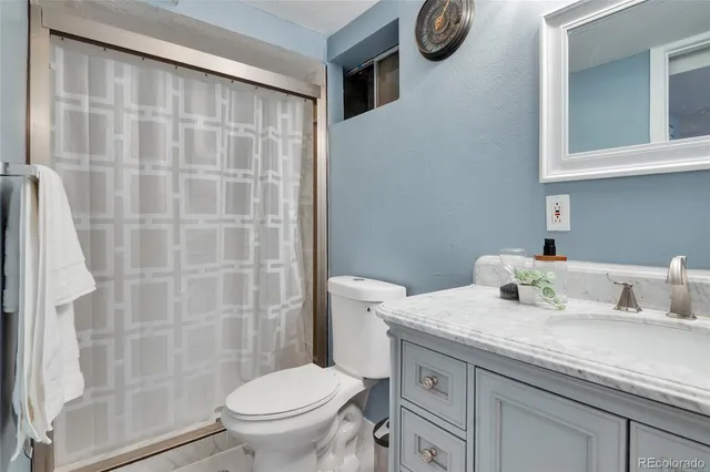 a bathroom with a granite countertop sink a toilet and a shower