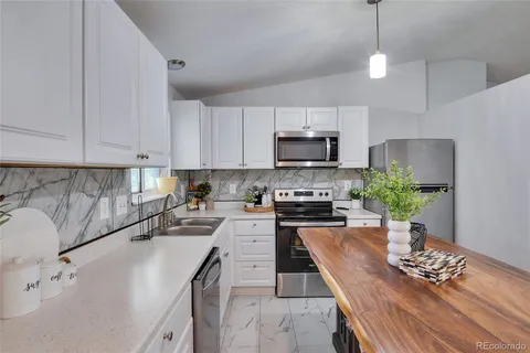 a kitchen with stainless steel appliances a stove a sink a microwave a dining table and chairs