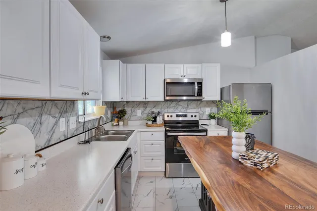 a kitchen with stainless steel appliances a stove a sink a microwave a dining table and chairs