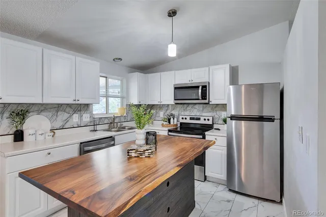 a kitchen with refrigerator a stove cabinets a sink a stove and chairs