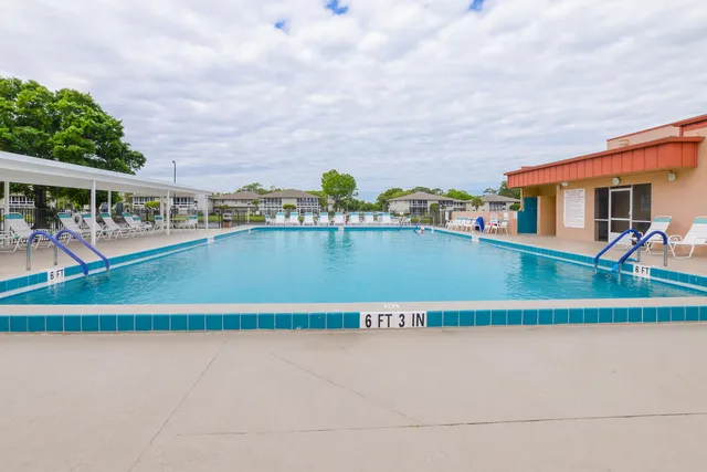 a view of a swimming pool with a lawn chairs and floor to ceiling window