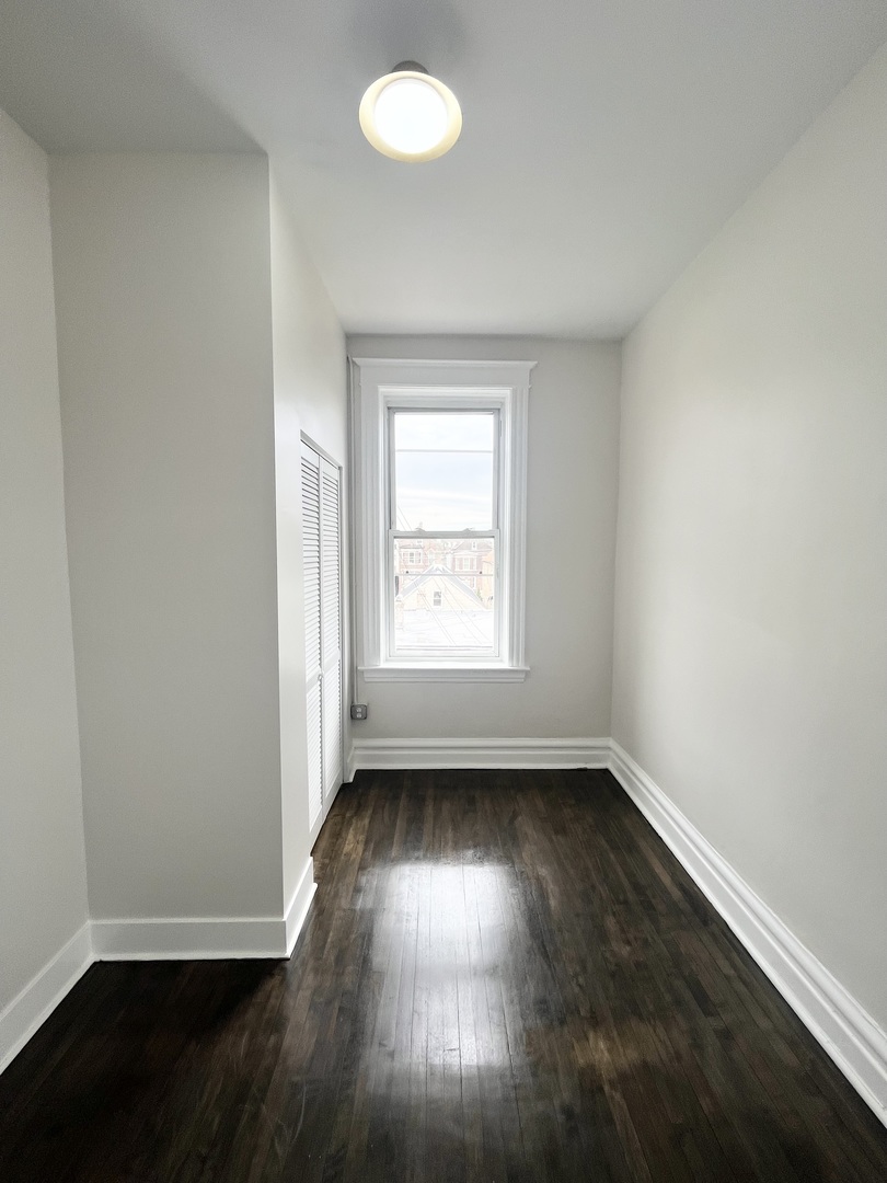 2512 South Trumbull Avenue, Unit 2R Chicago, IL 60623 - Photo 4 of 13 an empty room with wooden floor and windows