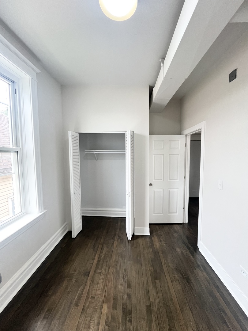 2512 South Trumbull Avenue, Unit 2R Chicago, IL 60623 - Photo 6 of 13 an empty room with wooden floor and windows