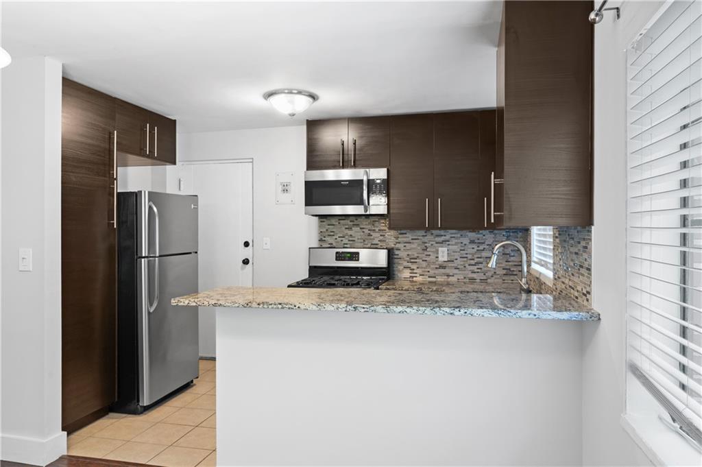 1370 Chalmette Drive Northeast, Unit 2 Atlanta, GA 30306 - Photo 9 of 16 a kitchen with stainless steel appliances kitchen island granite countertop a refrigerator and a stove top oven