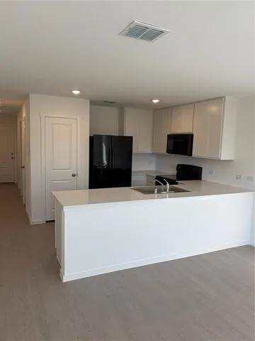a living room with stainless steel appliances white cabinets and a couch
