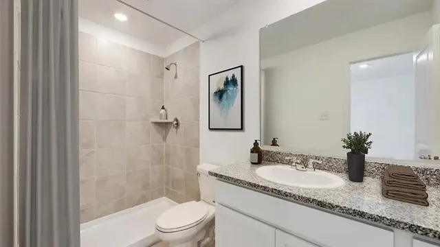 a bathroom with a granite countertop sink a toilet a mirror a vanity and shower