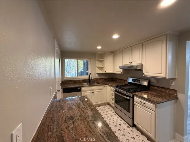 a kitchen with granite countertop a sink stove and cabinets