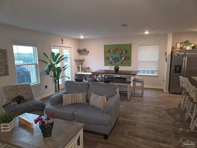 a kitchen with stainless steel appliances granite countertop a stove a refrigerator a sink a dining table and chairs