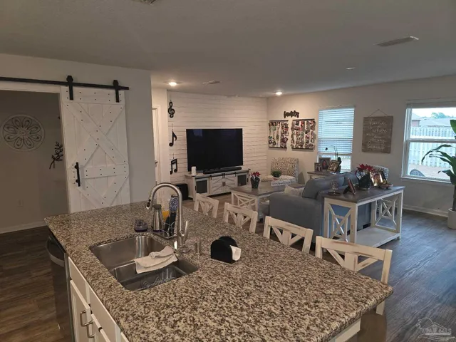 a kitchen with a sink a counter and a flat screen tv
