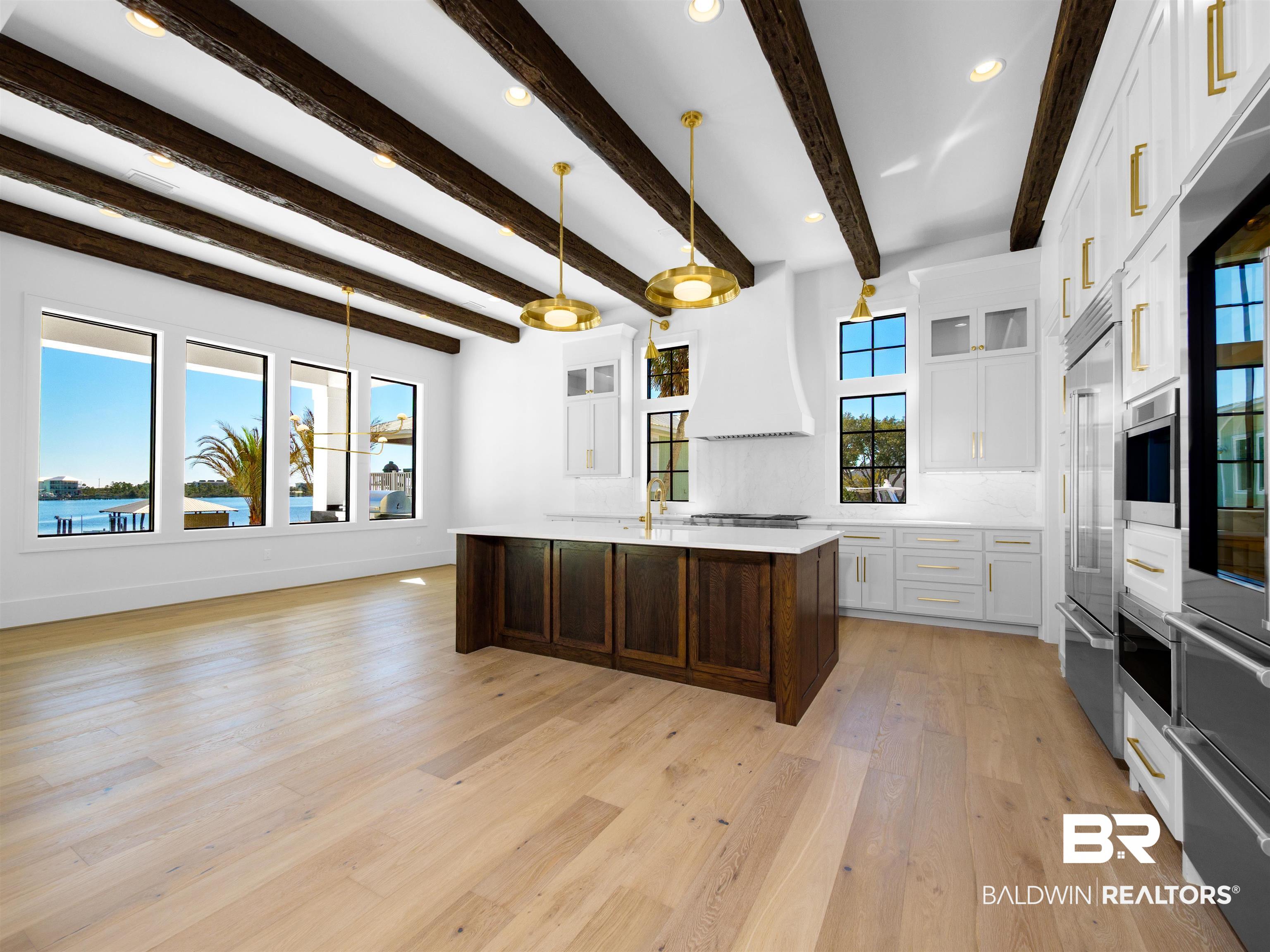 31292 River Road Orange Beach, AL 36561 - Photo 6 of 48 Kitchen featuring a kitchen island, white cabinetry, light countertops, light wood-type flooring, and custom exhaust hood