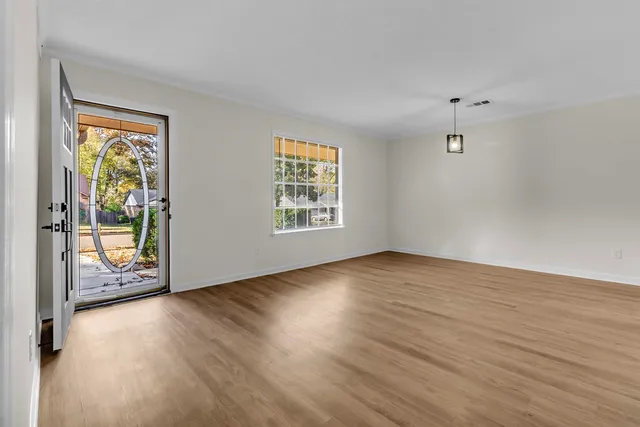 an empty room with wooden floor and windows