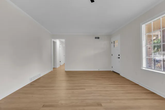 a view of an empty room with wooden floor and a window