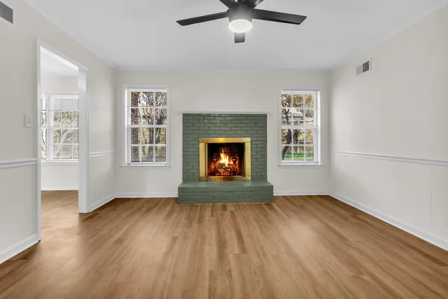 an empty room with wooden floor fireplace and windows