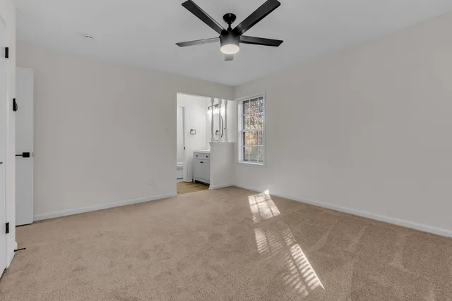 an empty room with windows and fan