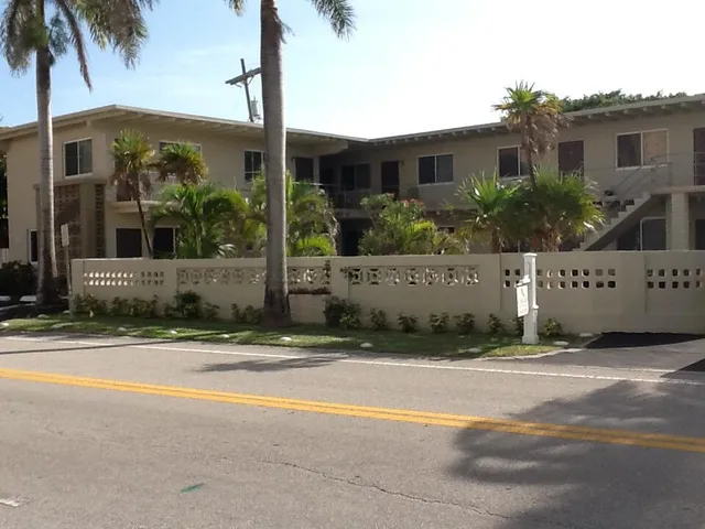 a view of a house with a yard and palm trees