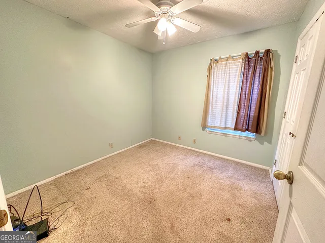 an empty room with windows and fan