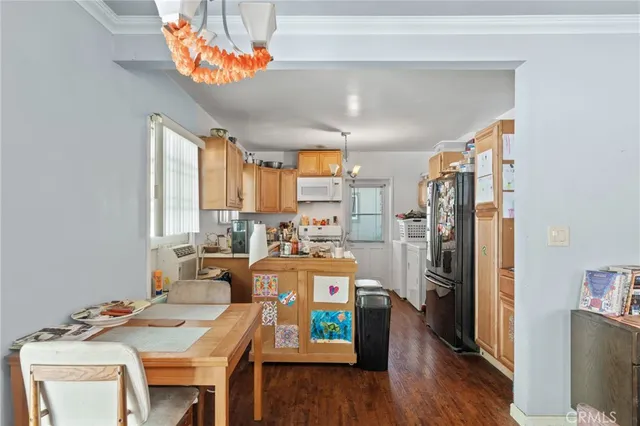 a kitchen with stainless steel appliances granite countertop a refrigerator a microwave oven a sink dishwasher and a dining table with wooden floor