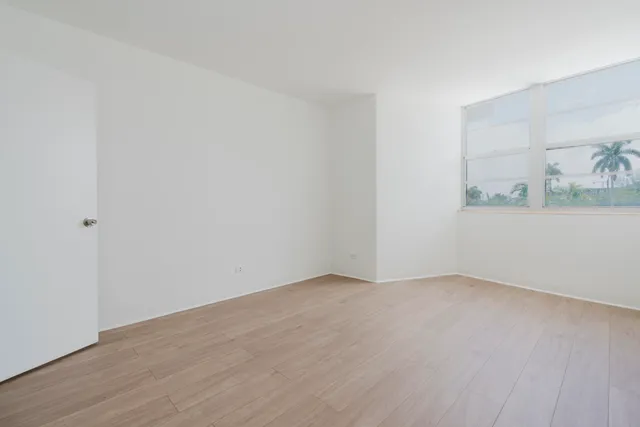 an empty room with wooden floor and window