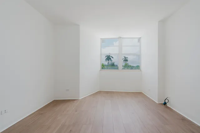 a view of an empty room with wooden floor and closet