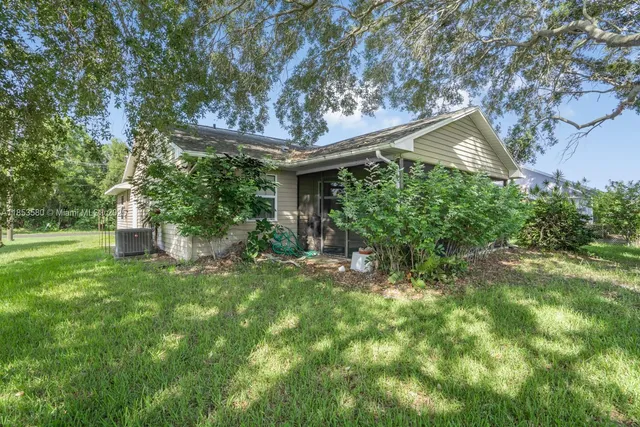 a backyard of a house with plants and large tree