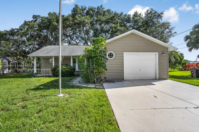 a backyard of a house with plants and barbeque oven