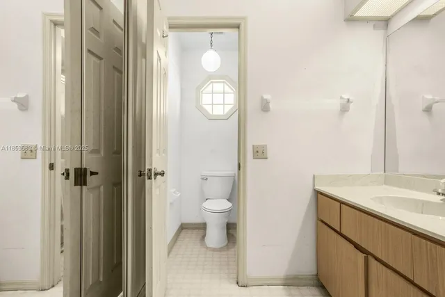 a bathroom with a granite countertop toilet a sink and a mirror