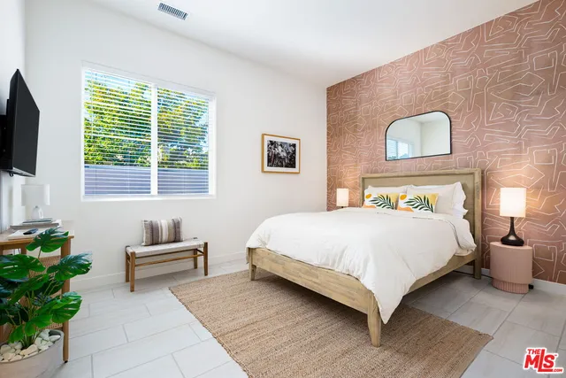 a bedroom with a large bed and a potted plant
