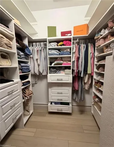 a view of walk in closet with clothes and shoes