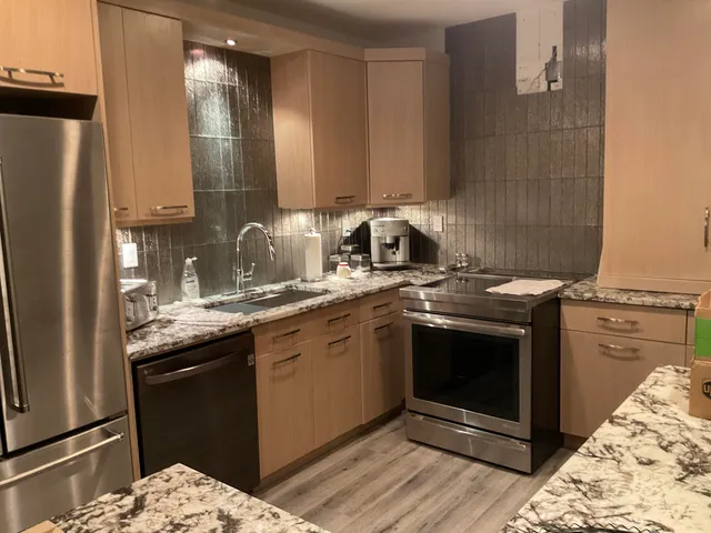 a kitchen with stainless steel appliances granite countertop a stove a sink and a refrigerator