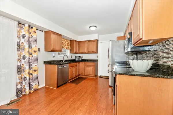 a kitchen with stainless steel appliances granite countertop a refrigerator a stove top oven a sink and dishwasher