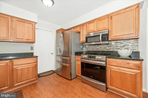 a kitchen with granite countertop a refrigerator stove and sink