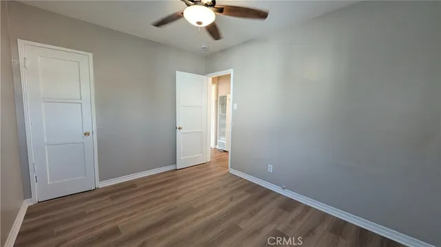 an empty room with wooden floor fan and window