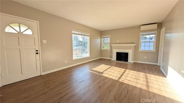 an empty room with windows a fireplace and wooden floor