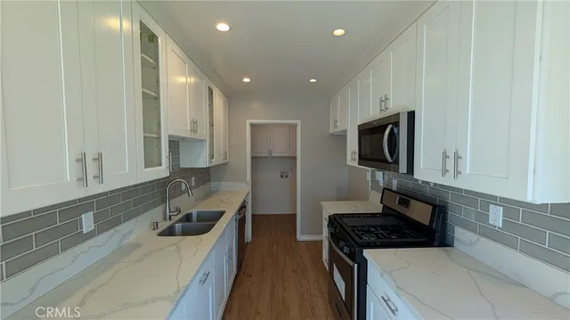 a kitchen with granite countertop a sink dishwasher stove and cabinets