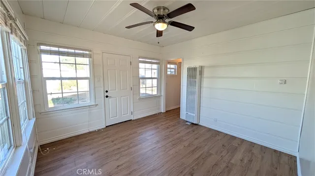 a view of empty room with wooden floor and fan