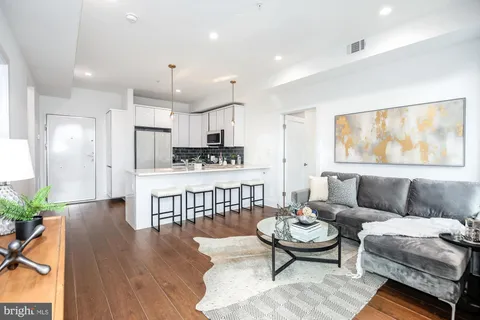 a living room with furniture a rug kitchen view and a window