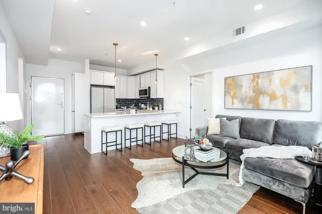 a living room with furniture a rug kitchen view and a window