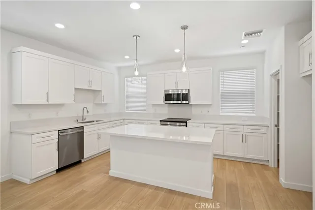 a kitchen with stainless steel appliances granite countertop a stove a sink dishwasher and a refrigerator with wooden floor