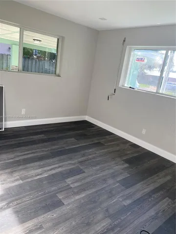 a view of a room that has wooden floor and window
