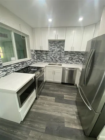 a kitchen with stainless steel appliances granite countertop a stove a sink and a microwave