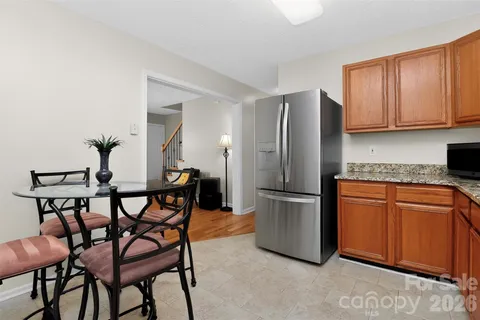 a kitchen with stainless steel appliances granite countertop a refrigerator a stove a sink dishwasher and white cabinets with wooden floor
