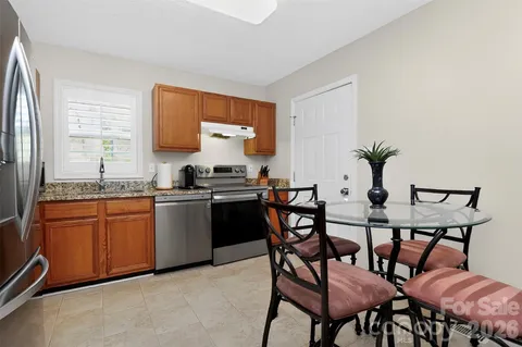 a kitchen with stainless steel appliances kitchen island granite countertop a table chairs in it and wooden floors