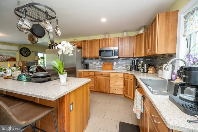 a kitchen with stainless steel appliances kitchen island granite countertop a table chairs in it and wooden floors