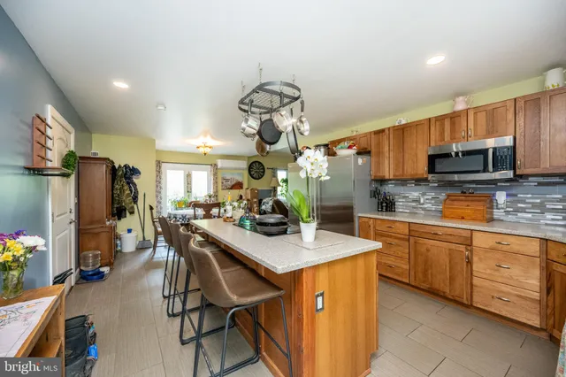 a kitchen with a sink dishwasher a stove a microwave oven and a dining table with wooden floor