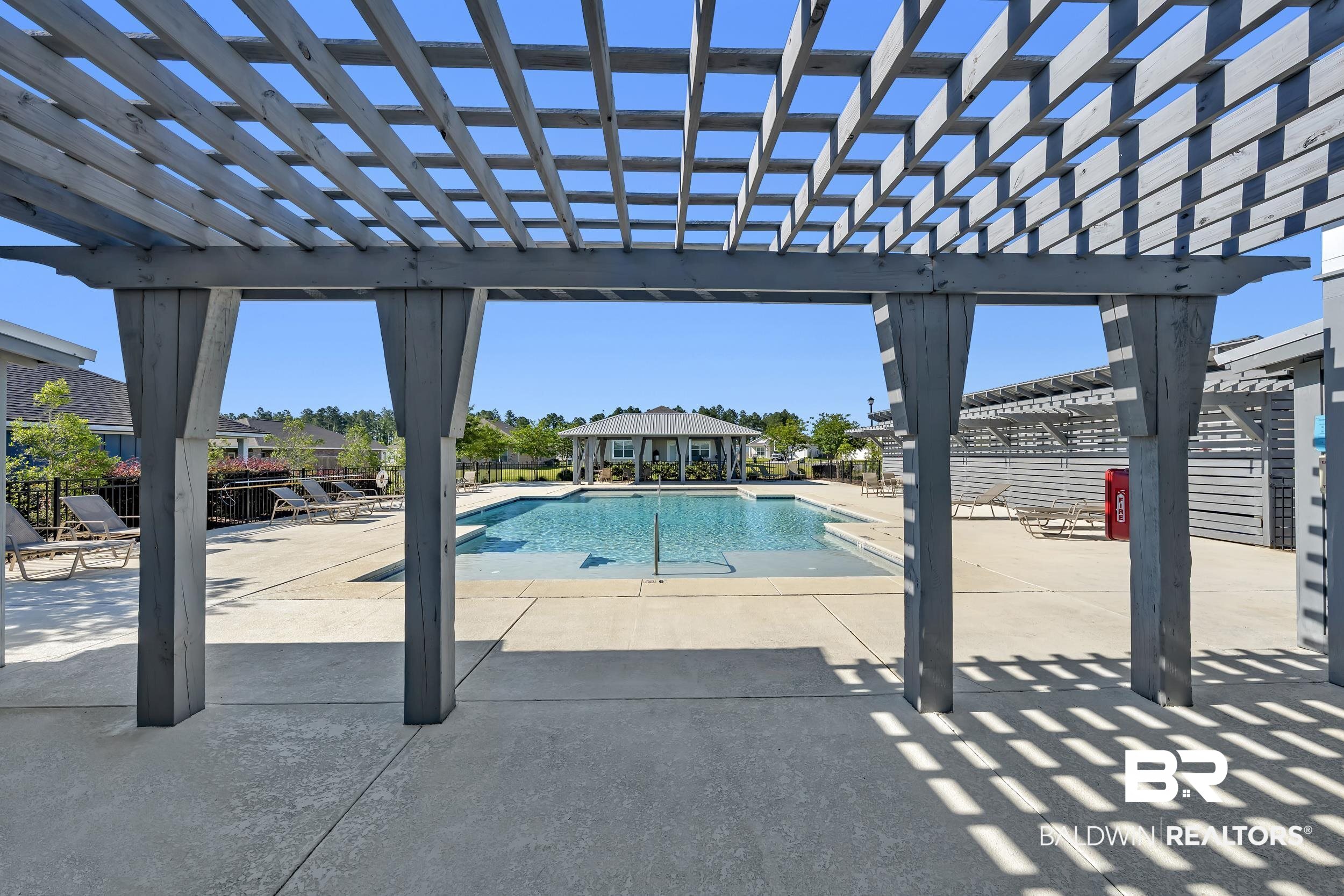 1228 Caper Avenue Foley, AL 36535 - Photo 38 of 54 Expansive outdoor pool area featuring a large swimming pool with concrete decking, surrounded by a lattice-style pergola